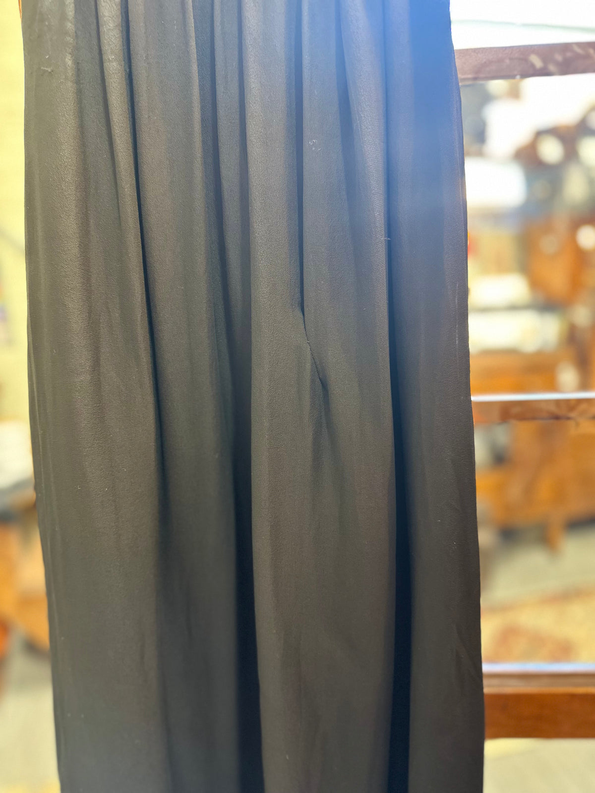 Close-up of the flowing black chiffon fabric showing the gown's soft gathered construction, draped texture and a small repair.