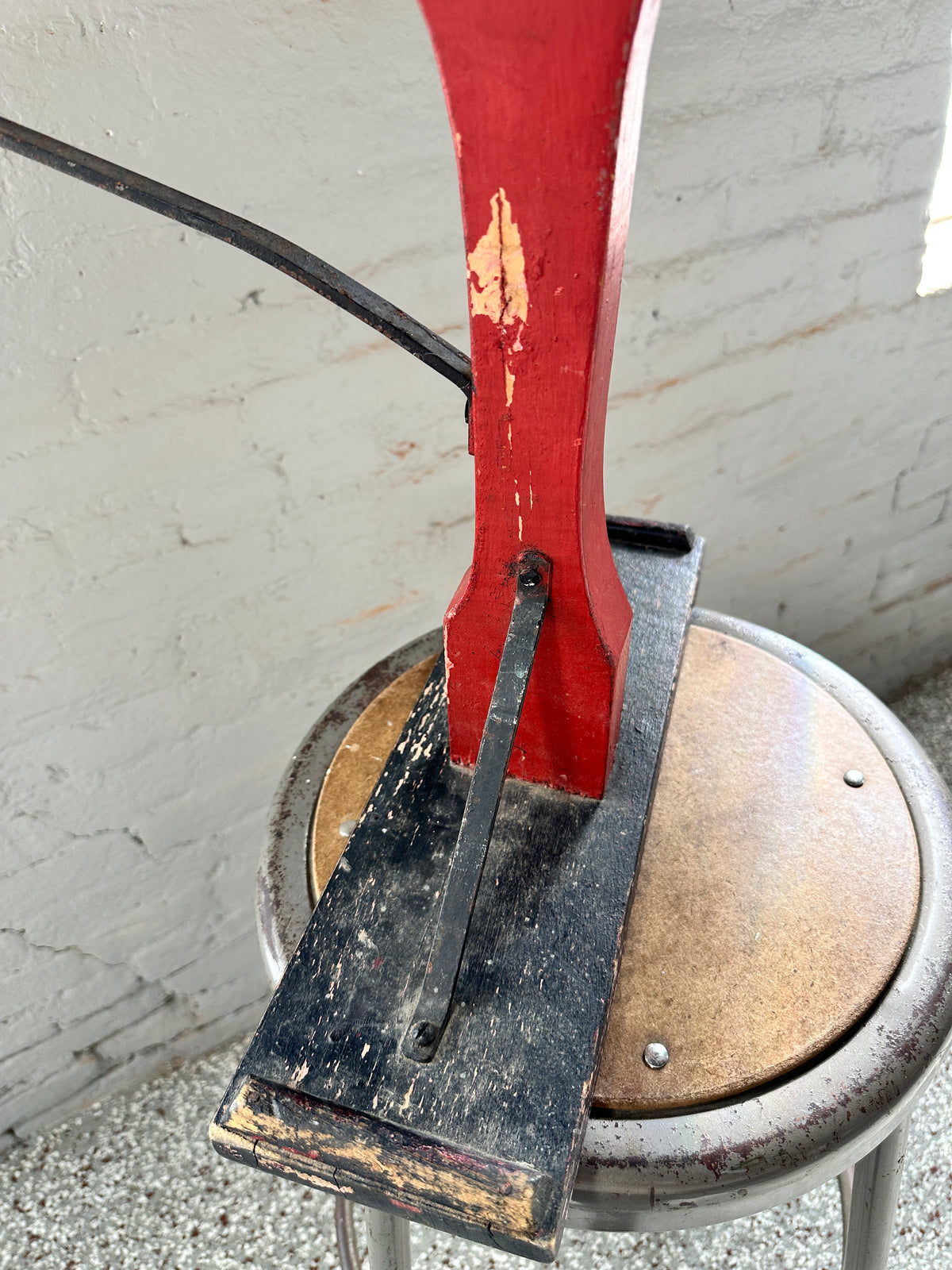 Close-up of antique jack jumper sled showing original red wooden upright, black metal brace and worn black seat.