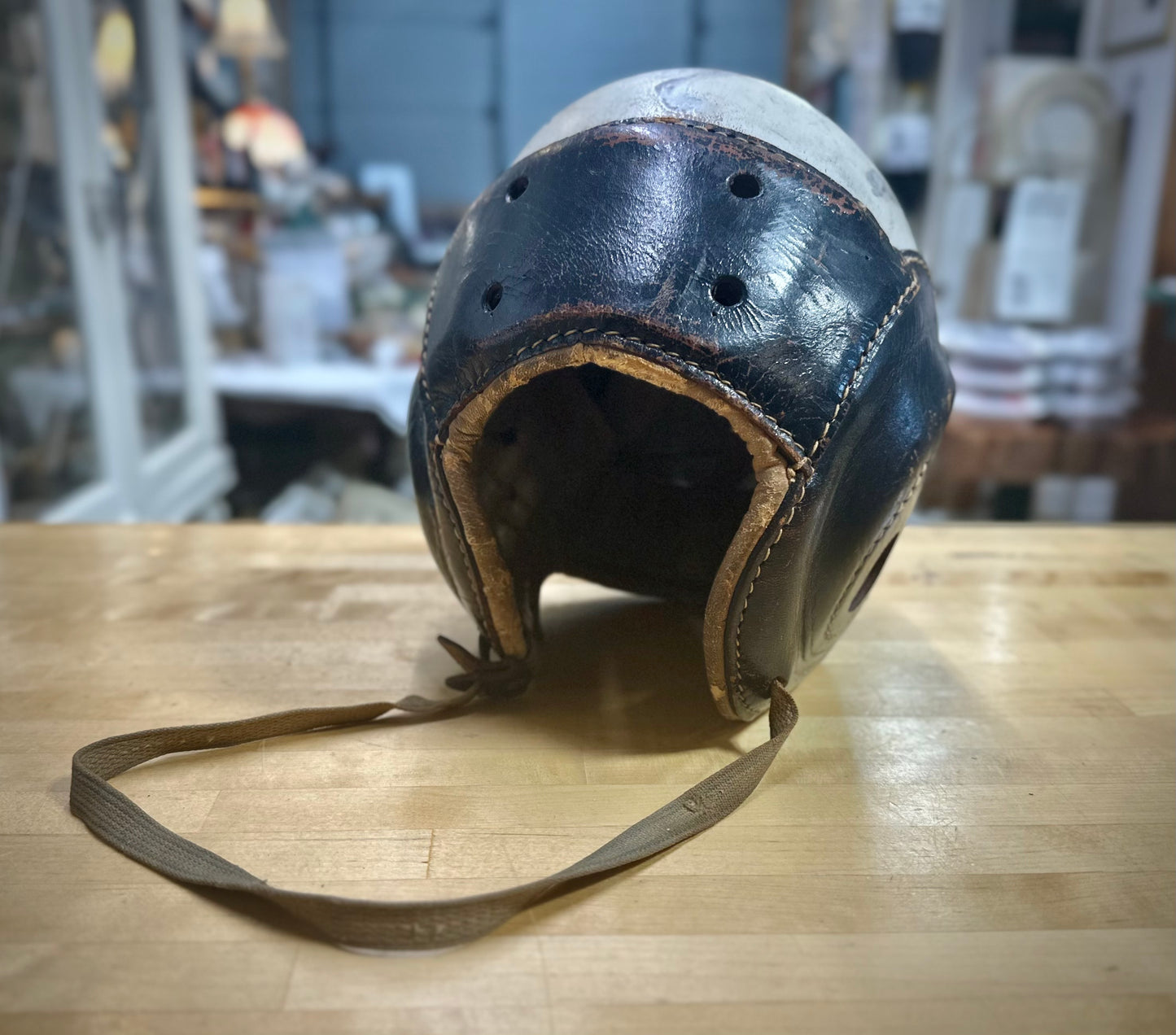 Vintage leather helmet with a chin strap on a wooden surface