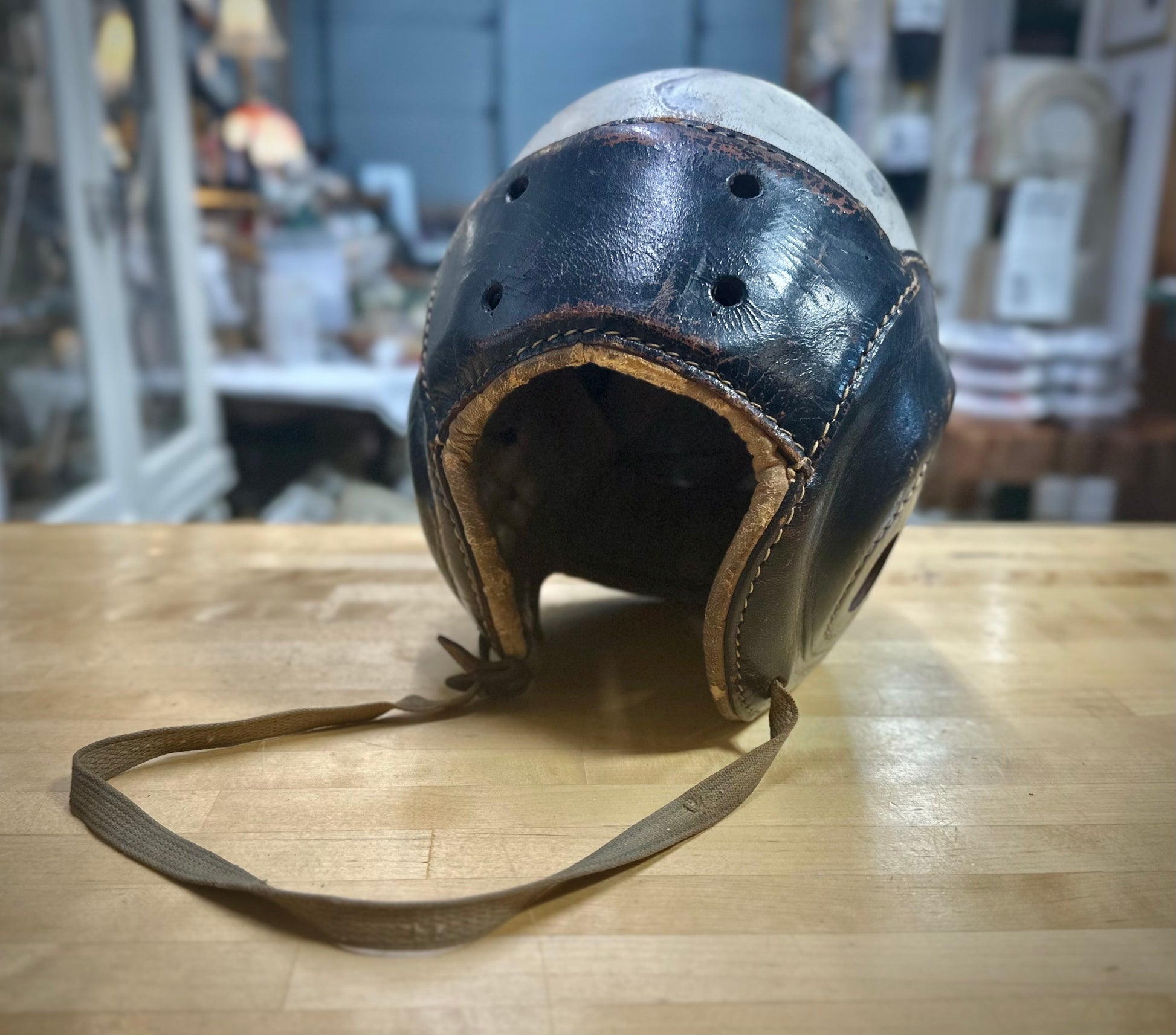 Vintage leather helmet with a chin strap on a wooden surface