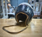 Vintage leather helmet with a chin strap on a wooden surface