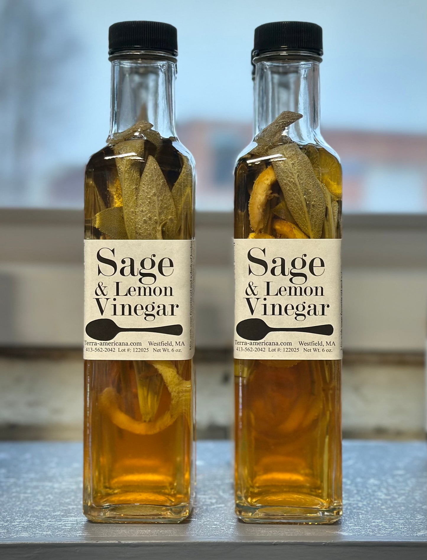Sage lemon vinegar bottle with fresh farm grown sage sprigs and lemon peel

