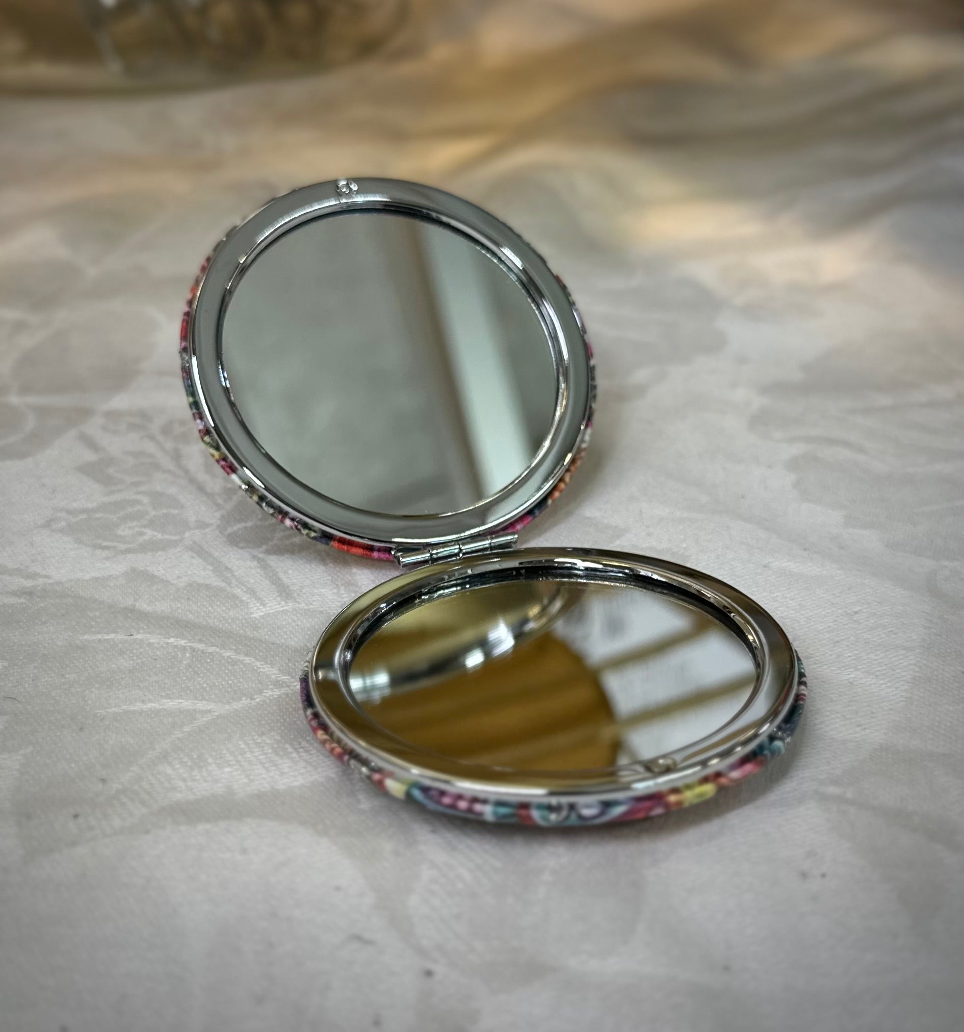 Open floral compact mirror showing dual mirror surfaces