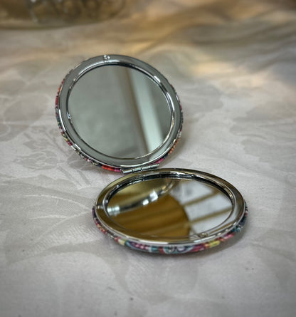 Open floral compact mirror showing dual mirror surfaces