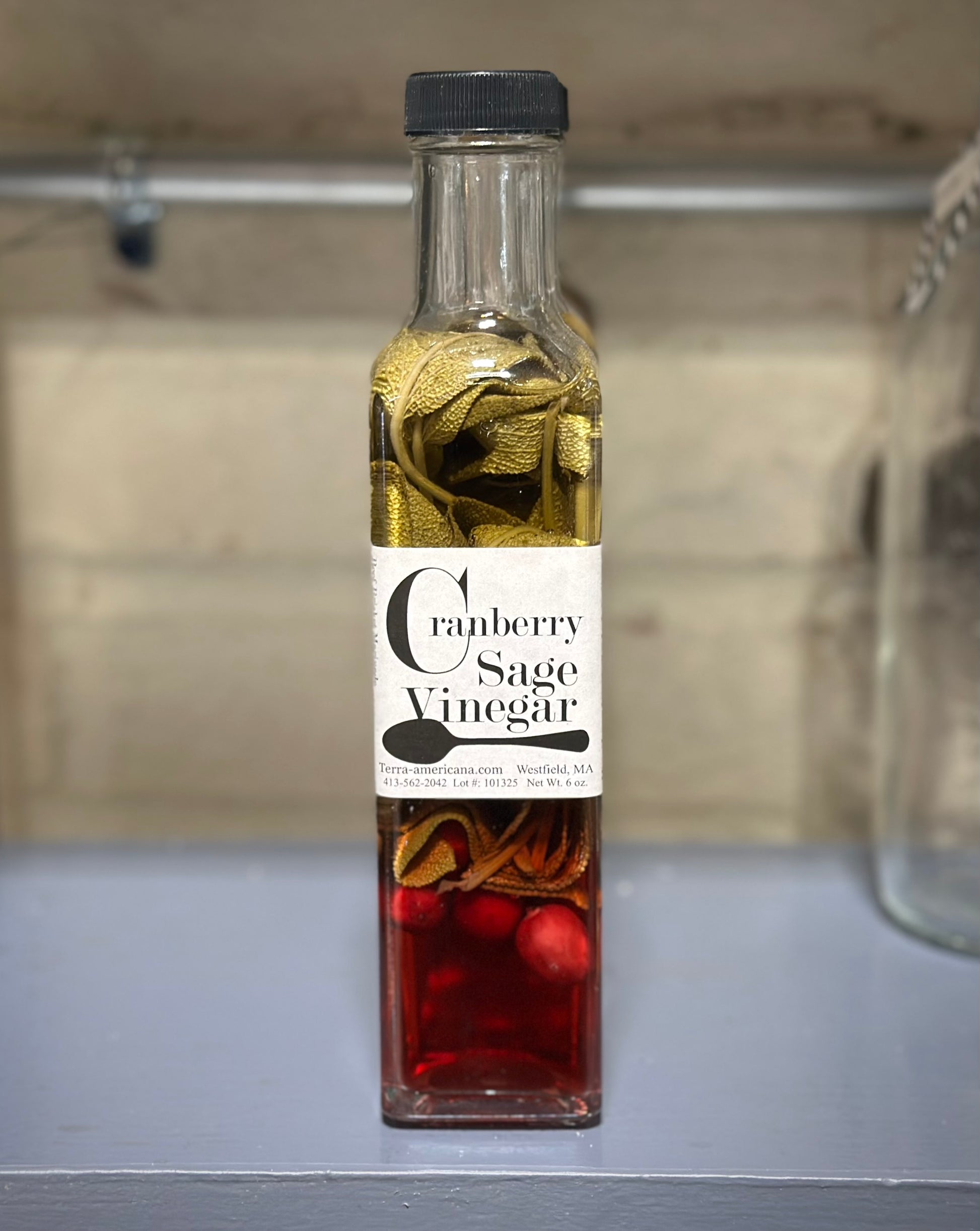 Cranberry sage vinegar bottle with fresh cranberries and sage leaves from farm