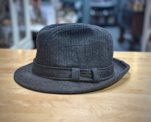 Gray fedora hat with a band on a wooden surface