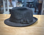 Gray fedora hat with a band on a wooden surface