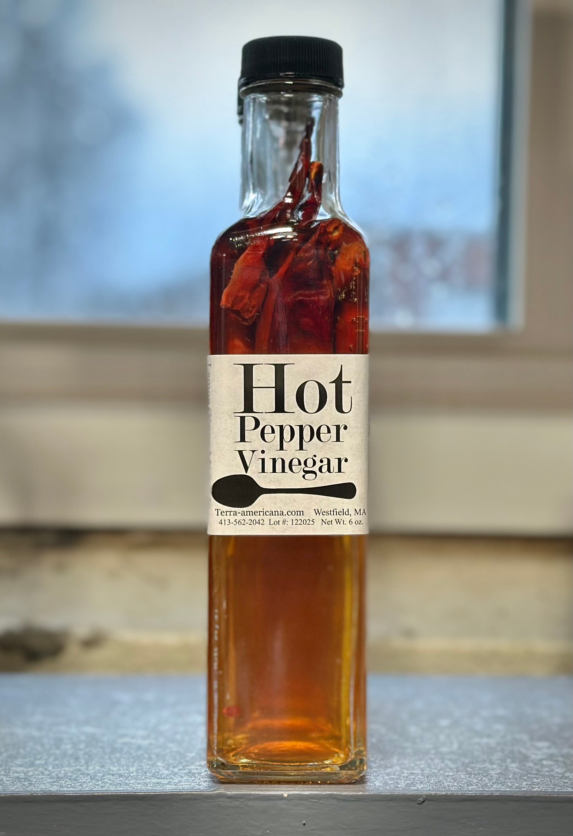 Hot pepper vinegar bottle with fresh red and green hot peppers