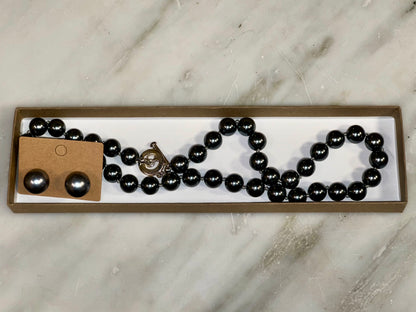 Black beaded necklace and earrings on a marble surface