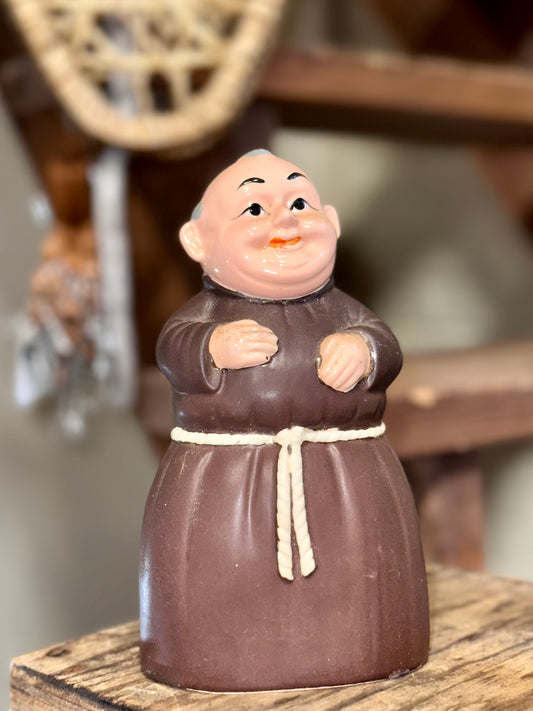 Vintage ceramic monk coin bank wearing a brown robe with white rope belt.