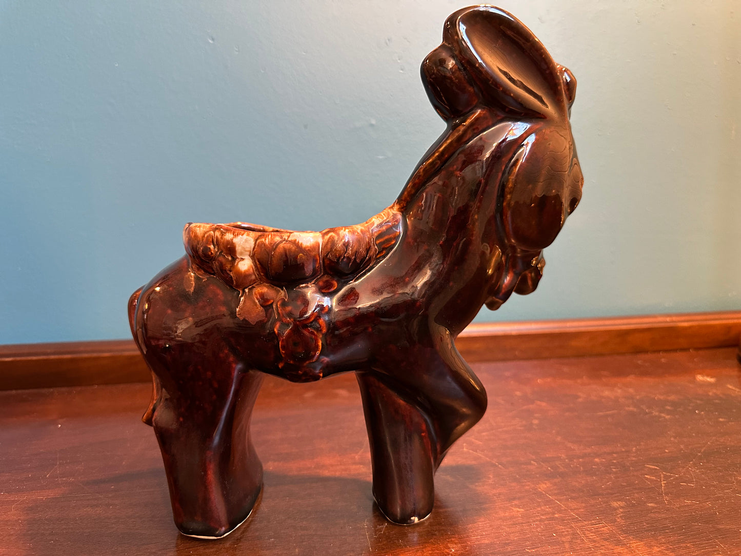 Side profile of large vintage donkey planter featuring raised saddle and floral details