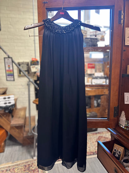Full-length front view of the vintage Saks Fifth Avenue black evening gown featuring a sleeveless flowing chiffon silhouette and ornate black beaded neckline.
