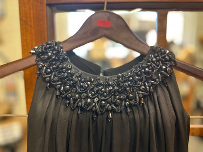 Close-up front view of the vintage Saks Fifth Avenue black gown showing the heavily embellished rounded neckline with black faceted beads, sequins, seed beads and dangling beadwork.