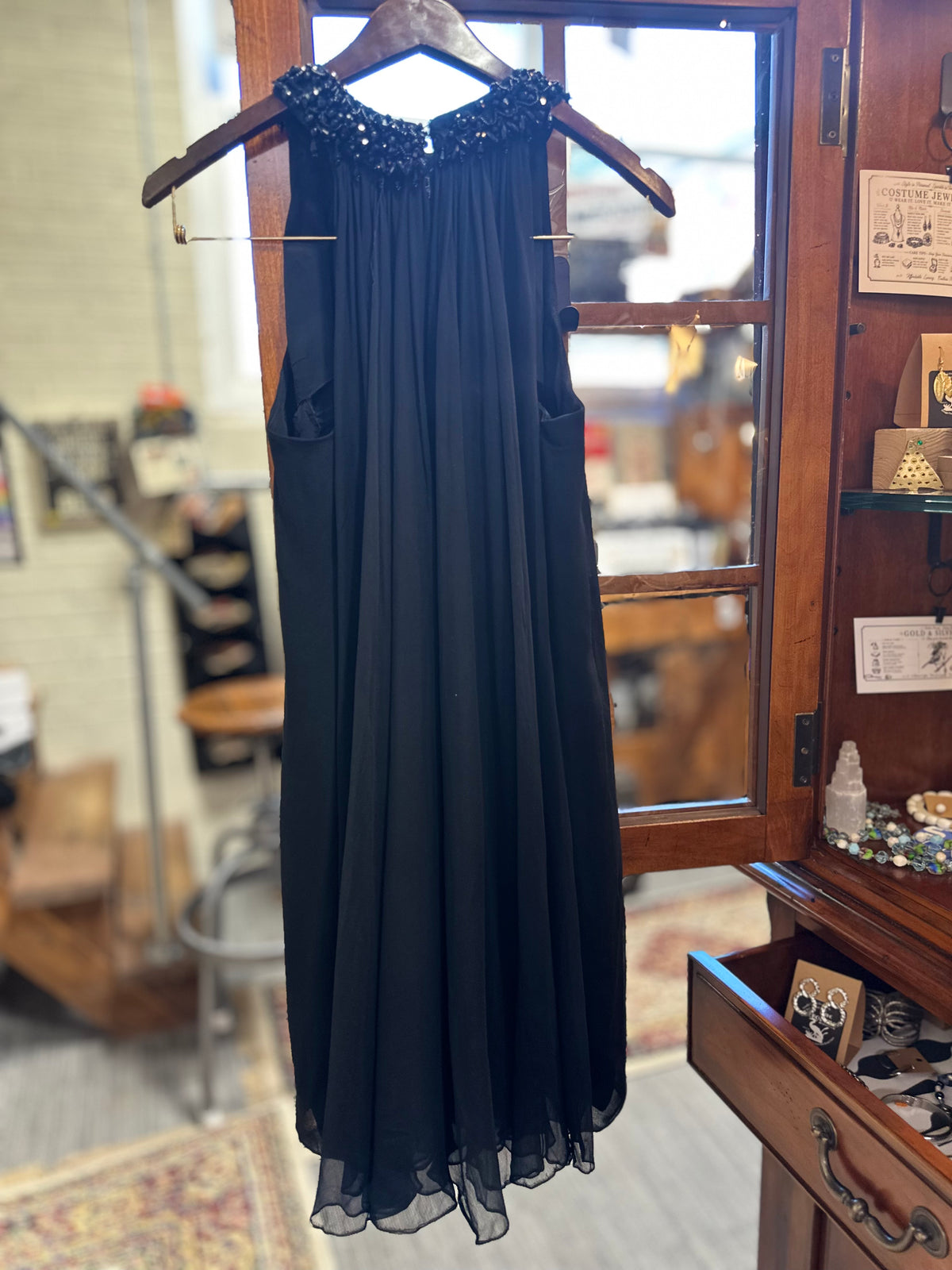 Full-length back view of the vintage black Saks Fifth Avenue evening gown, showing the flowing gathered chiffon silhouette, embellished shoulders and side details.
