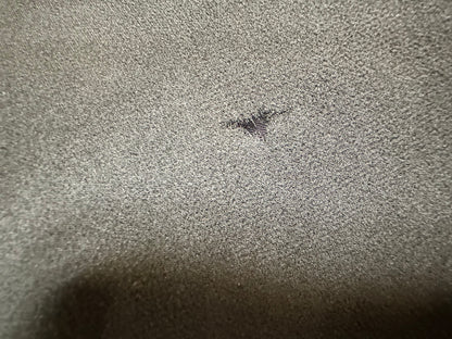 Close-up condition photo showing a small hole or tear in the sheer black fabric of the vintage evening gown.
