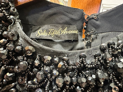 Close-up of the Saks Fifth Avenue label inside a vintage black evening gown, surrounded by intricate black faceted bead, seed bead and sequin embellishment.
