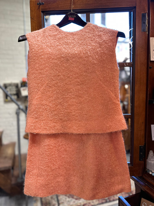 Front view of a vintage coral pink bouclé two-piece skirt ensemble, approximately 1960–1965, with matching sleeveless top and lined skirt.