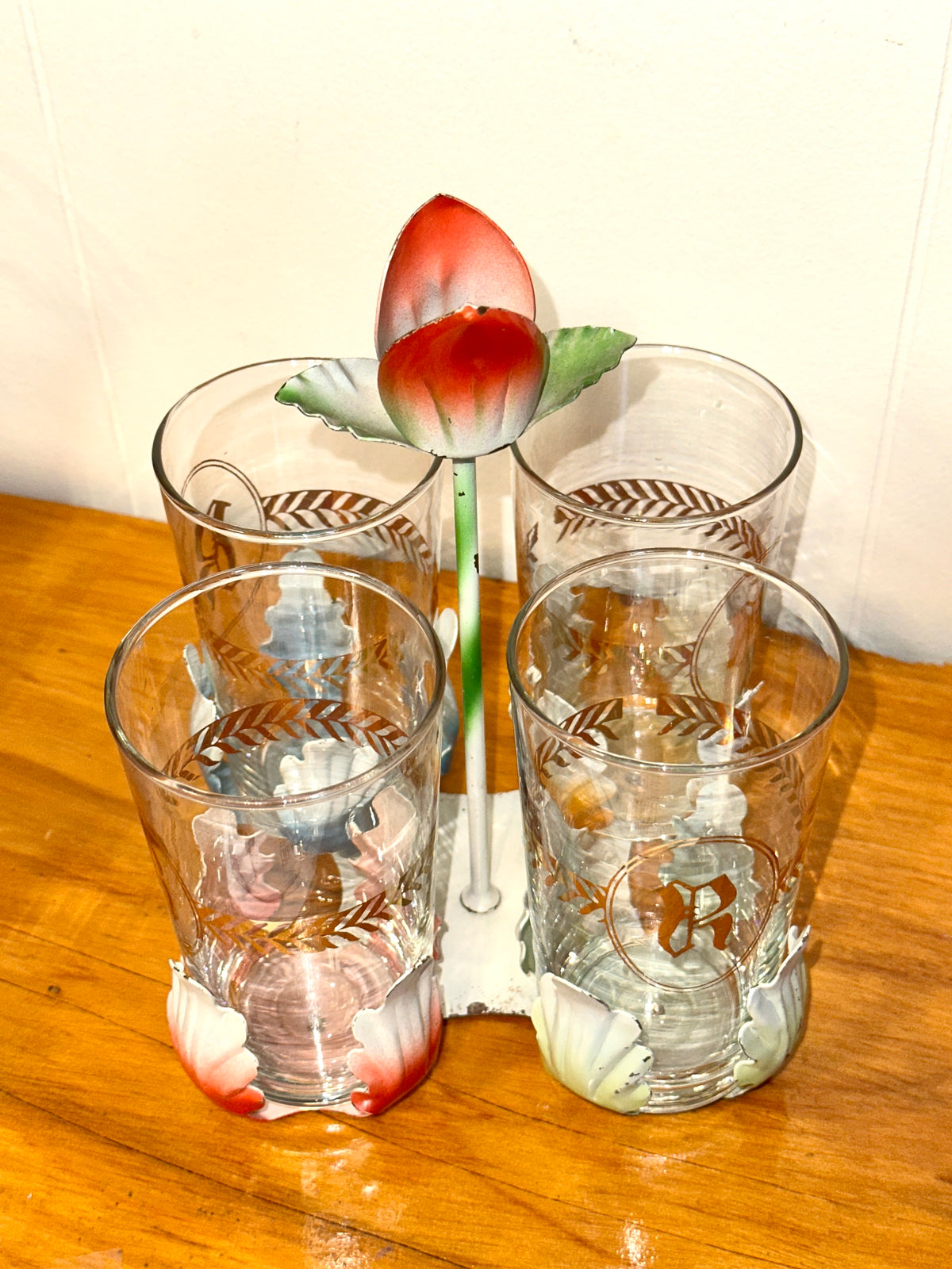 Four vintage glasses with colorful floral accents and gold leaf design