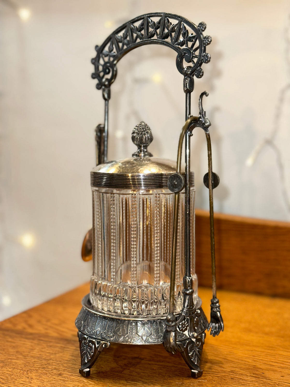 Vintage glass biscuit jar showing its intricate silver-tone metal base, decorative feet, and detailed framework.