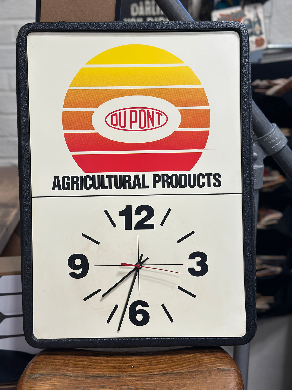 Front view of vintage DuPont Agricultural Products advertising wall clock showing the colorful DuPont logo, agricultural products lettering, clock face, and black molded frame.