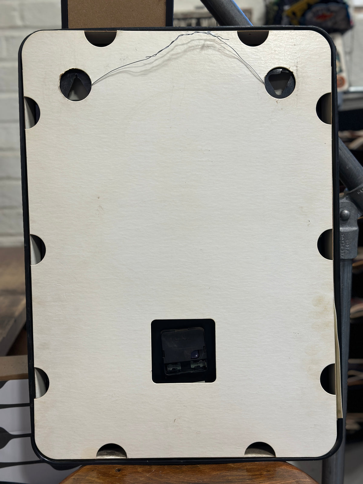 Rear view of the vintage DuPont advertising clock showing the cream-colored backing, black frame, hanging wire, and quartz movement access area.