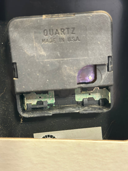 Close-up of the rear quartz clock movement showing the metal housing marked “QUARTZ” and “MADE IN USA,” with visible age and wear.