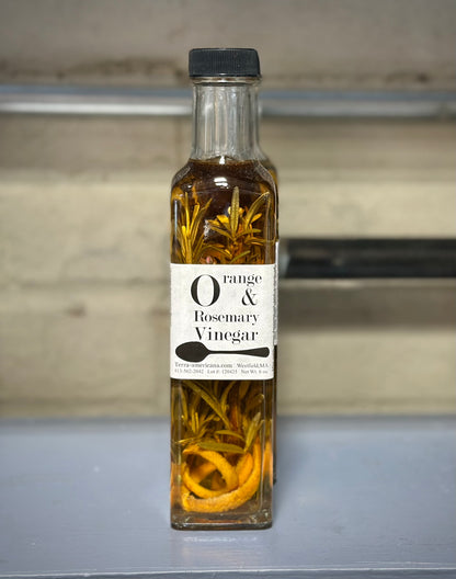 Orange rosemary vinegar bottle with fresh oranges and rosemary sprigs