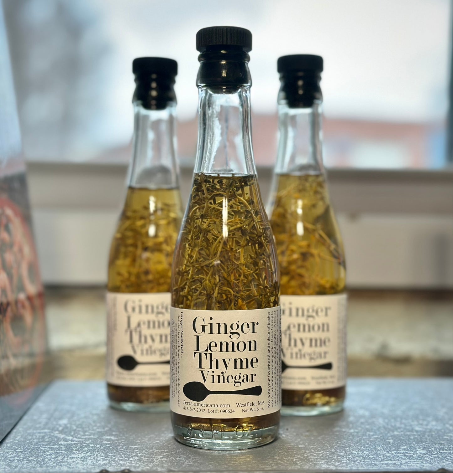 Ginger lemon thyme vinegar bottle with fresh ginger root, lemon thyme sprigs and lemon peel