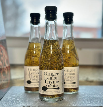 Ginger lemon thyme vinegar bottle with fresh ginger root, lemon thyme sprigs and lemon peel