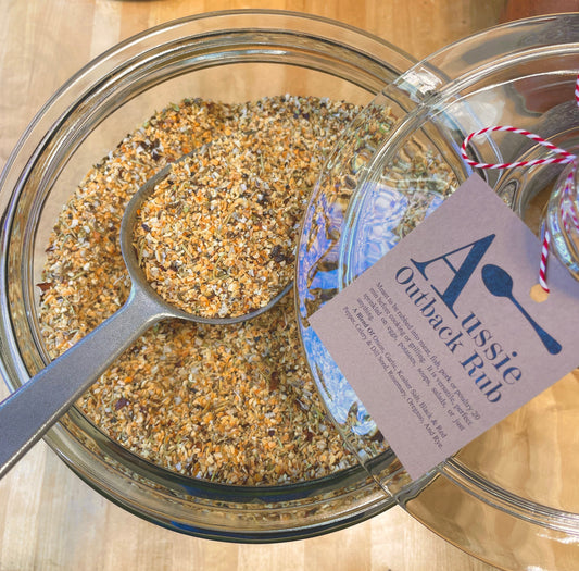 Aussie Outback Rub seasoning blend displayed in a glass jar with a metal scoop