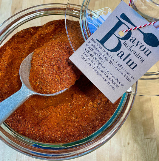 Bayou Blackening Balm Cajun seasoning displayed in a glass jar with a metal scoop