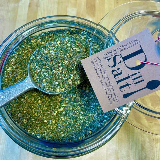 Dill Salt seasoning blend displayed in a glass jar with a metal scoop